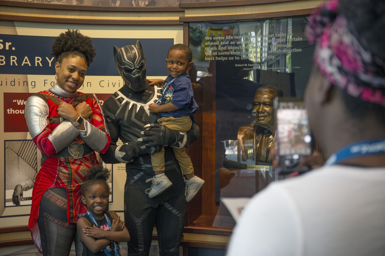 Okoye and T'Challa give the Wakandan salute with a young fan.